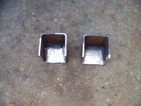 1985 Ford Bronco - Two metal brackets are shown on a concrete surface. The registry label indicates a 1985 Ford Bronco, but the image shows only parts.