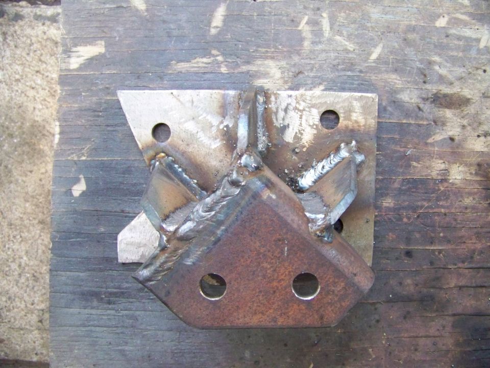 Welded steel bracket with multiple mounting holes, resting on a wooden surface