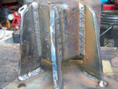 1985 Ford Bronco - A close-up view of a heavily welded metal bracket, showing the texture of the welds and some surface rust.