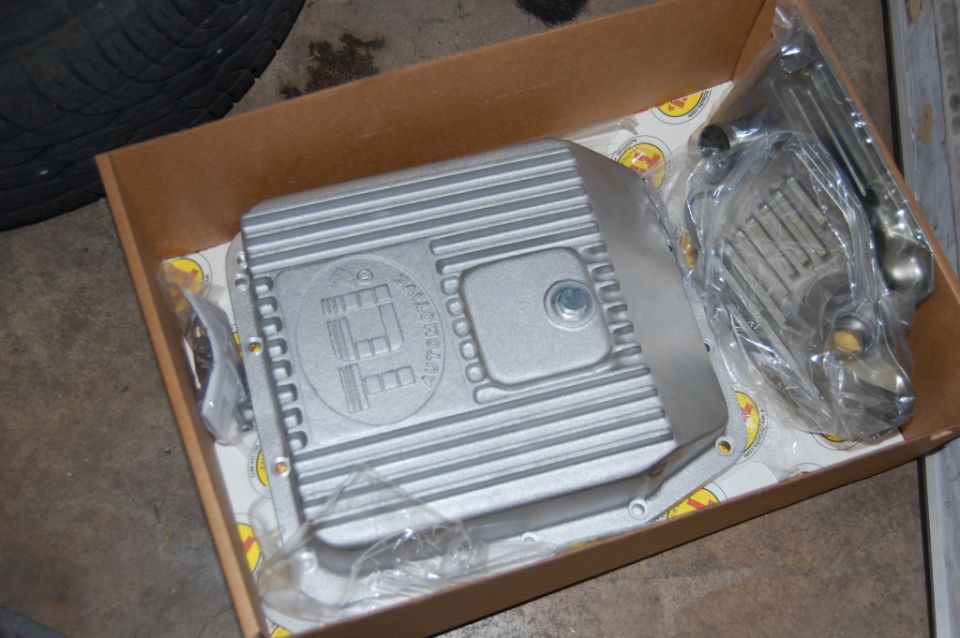 Aluminum transmission pan and some other parts in a box. There's a tire in the upper left