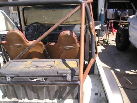 1987 Suzuki Samurai - The interior of a 1987 Suzuki Samurai is visible, along with a roll cage and a storage box in the bed.