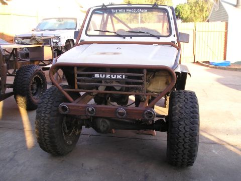 1987 Suzuki Samurai - This 1987 Suzuki Samurai features a custom front bumper and roll cage, with a prominent SUZUKI badge on the grille.