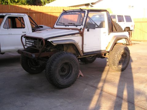 1987 Suzuki Samurai - Modified 1987 Suzuki Samurai sits next to a white pickup truck in a driveway.