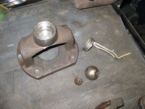 1994 Ford Bronco - Disassembled driveshaft U-joint yoke, bearing cap, and clip are laid out on a textured surface.