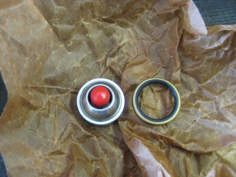 1994 Ford Bronco - A metal cap with a red ball and a rubber seal are laid out on crumpled brown paper.