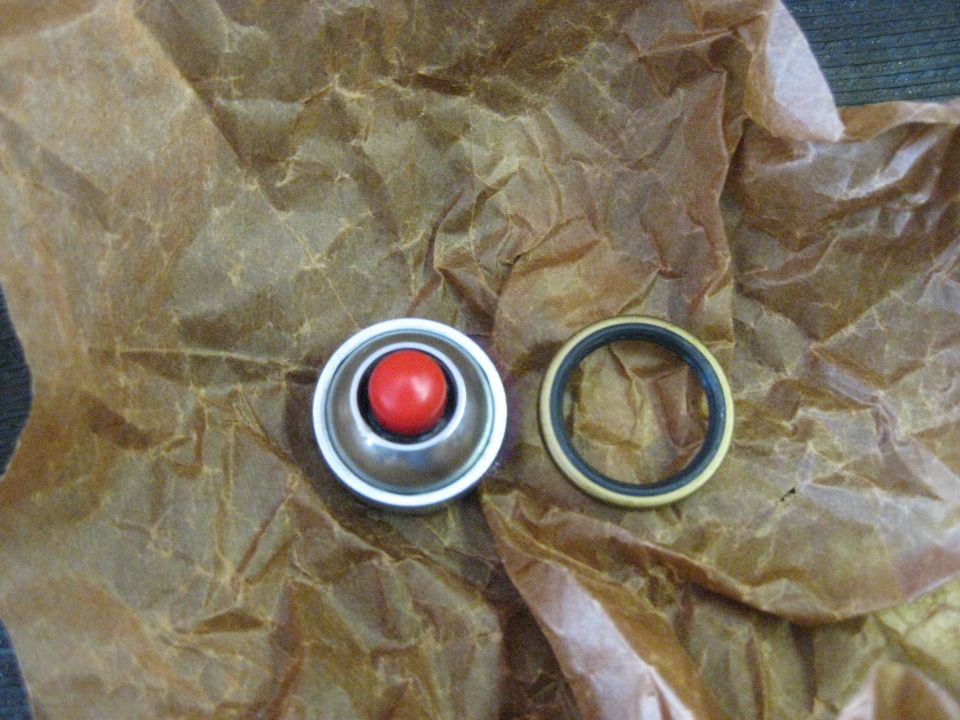 Metal cap with red ball and a rubber seal on brown paper