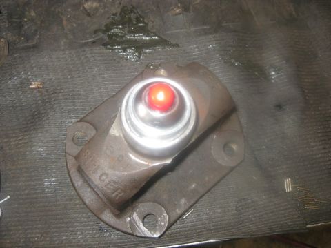 1994 Ford Bronco - A driveshaft component with a red bearing is shown on a workbench, possibly awaiting repair or replacement.