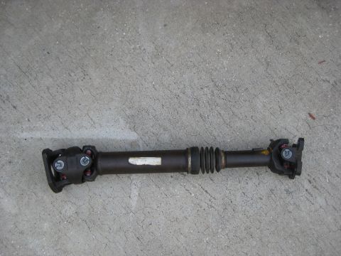 1994 Ford Bronco - Driveshaft with U-joints and a rubber boot, lying on concrete. White label on shaft.