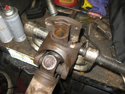 1994 Ford Bronco - Close-up of a rusty driveshaft U-joint assembly, likely undergoing repair or maintenance.