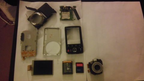 2000 Mercury Grand Marquis - Various electronic components, including a phone's internal parts and a camera module, are spread out on a white surface.