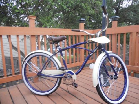 1953 Ford Mainline - A blue and white cruiser bicycle is parked on a wooden deck with a railing in the background.