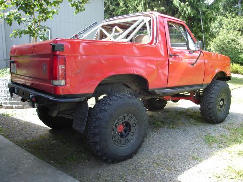 1989 Ford Bronco - This modified red Ford Bronco, likely from the late 1980s, sits on large off-road tires.