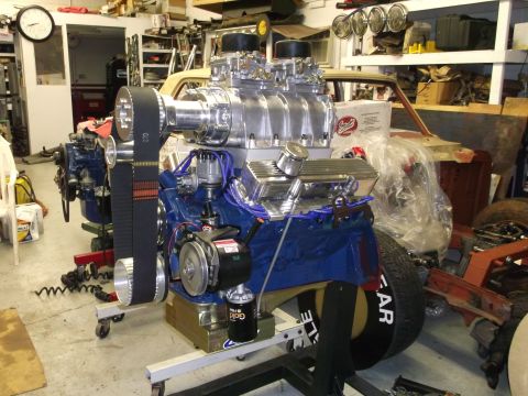 1971 Ford Ranchero - A powerful V8 engine with a supercharger and dual carburetors is displayed on a stand in a workshop.