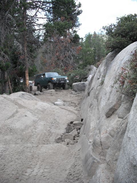 1991 Ford Bronco - A green 1991 Ford Bronco tackles a challenging rocky trail, with another vehicle visible in the background.