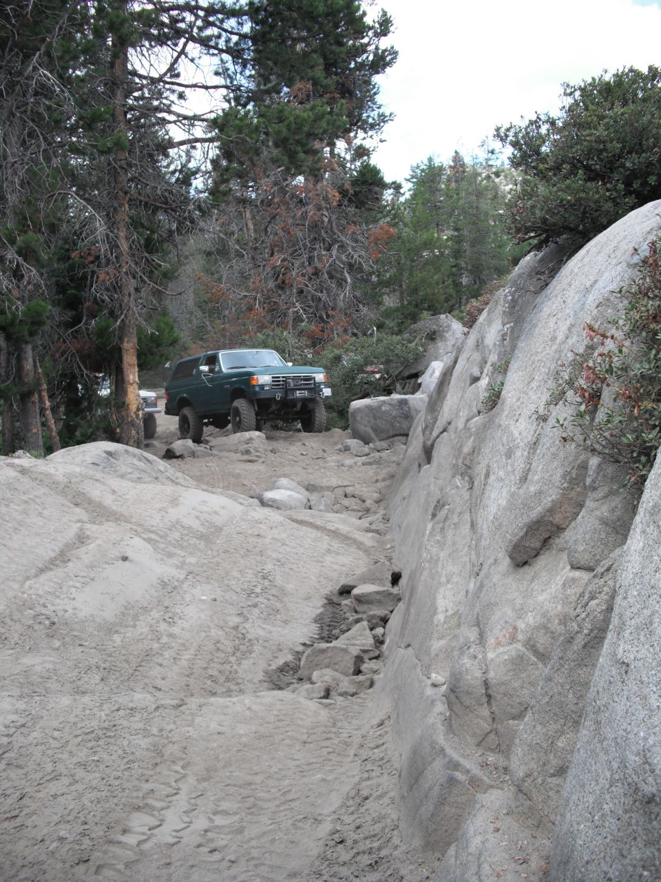 Green 1991 Ford Bronco navigating a rocky off-road trail