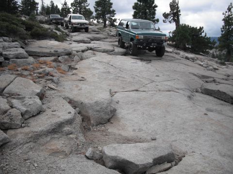 1991 Ford Bronco - Several SUVs navigate a challenging rocky trail under a cloudy sky.