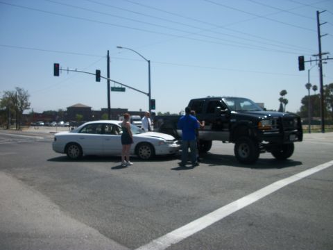 2001 Ford F-250 - Two vehicles are stopped at an intersection after a collision, with people standing nearby.