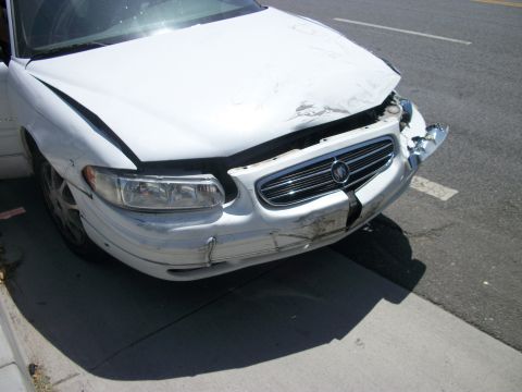 2001 Ford F-250 - The front of a white Buick sedan shows damage to the bumper and hood after an apparent collision.