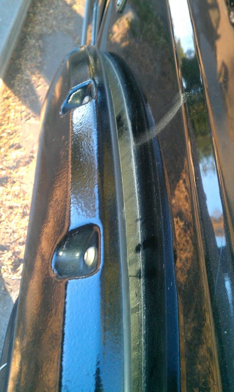 2001 Ford F-250 - A close-up view of a black truck fender shows a tow hook and the reflection of the surroundings.