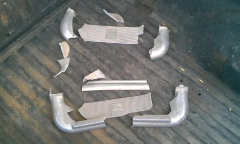2001 Ford F-250 - Damaged exhaust pipe components with heat shields are laid out on a dark, textured surface.