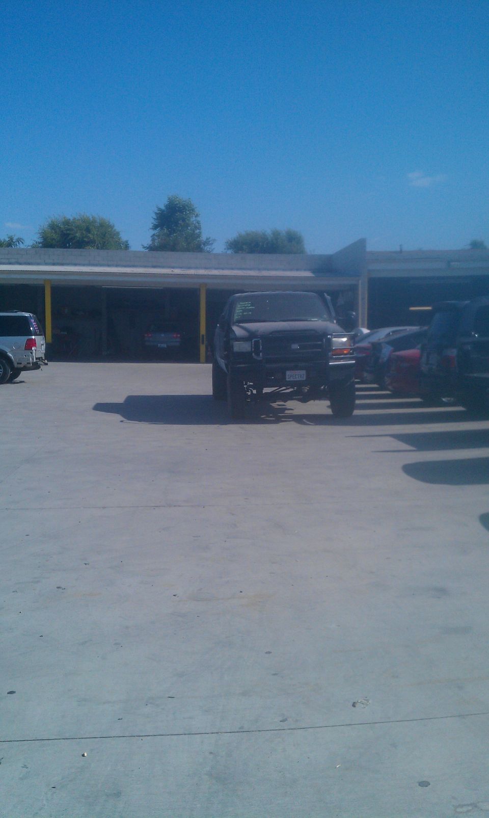 Lifted black pickup truck parked outside a building with other vehicles nearby