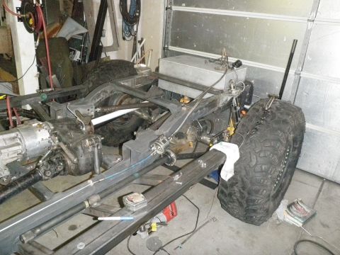 1961 International Scout 800 - The chassis and drivetrain components are visible, including a large fuel tank and a tire.