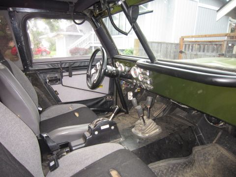 1974 Ford Bronco - The interior of a vehicle shows custom modifications including gauges and a roll cage.