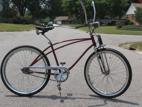 1994 Ford Bronco - A maroon cruiser bicycle with whitewall tires and chrome handlebars is parked on a suburban street.