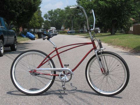 1994 Ford Bronco - A red cruiser bicycle with whitewall tires is parked on a residential street.