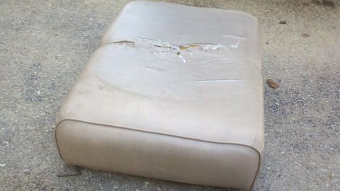 1900 Ford C-350 (Centurion Conversions) - A worn car seat with significant damage to its upholstery sits on a gravel surface.