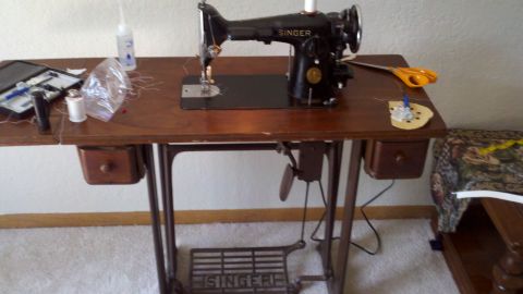 1900 Ford C-350 (Centurion Conversions) - A vintage Singer sewing machine sits on a wooden table, surrounded by sewing supplies.