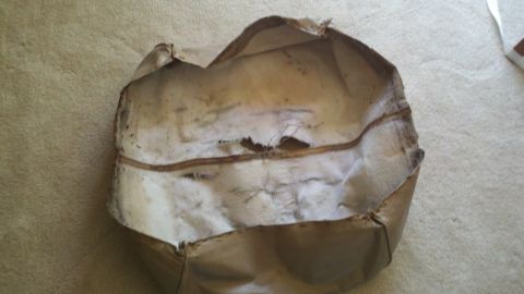 1900 Ford C-350 (Centurion Conversions) - A close-up view of a damaged, tan leather seat cover, showing signs of wear and tear.