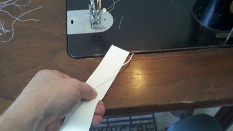 1900 Ford C-350 (Centurion Conversions) - Sewing machine with white thread and a hand holding a paper strip.