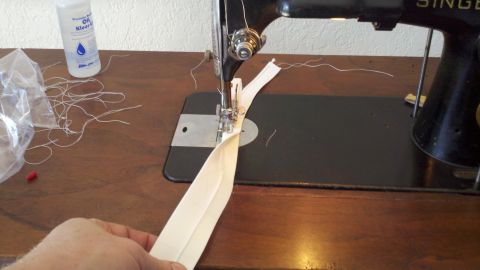 1900 Ford C-350 (Centurion Conversions) - A sewing machine is used to stitch a zipper, with a bottle of oil and loose threads visible on the wooden table.