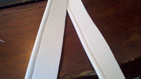 1900 Ford C-350 (Centurion Conversions) - Close-up of white trim pieces with visible stitching, set against a wooden background with a watermark.