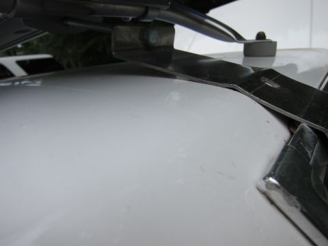 1991 Ford LTD Crown Victoria - Detail of a metal bracket and chrome trim on a white surface.
