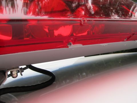 1991 Ford LTD Crown Victoria - Close-up of a red emergency light bar on a vehicle roof, showing mounting hardware and a cable.
