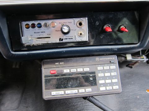 1991 Ford LTD Crown Victoria - Close-up of police radio equipment, including a siren control and a Motorola radio, installed in a vehicle.