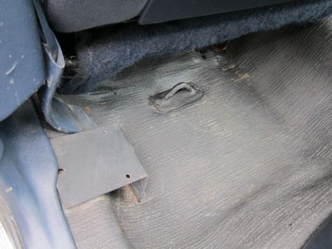 1991 Ford LTD Crown Victoria - The interior floor of a vehicle shows dark rubber matting and a metal bracket.