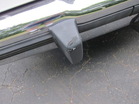 1991 Ford LTD Crown Victoria - Close-up of a damaged gray plastic bumper corner on a vehicle, showing wear and tear.