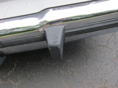 1991 Ford LTD Crown Victoria - Close-up of a vehicle's rear bumper corner, showing a black plastic protector and chrome trim detail.