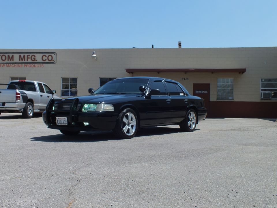 Black Mercury Crown Victoria with push bar parked outside machine shop