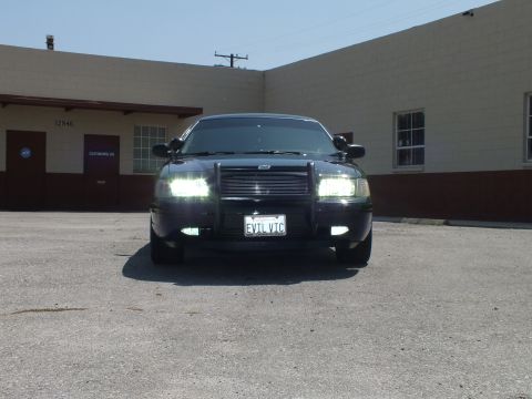 2003 Ford Crown Victoria - Direct front shot of a black full-size sedan, mesh grille and grille guard visible