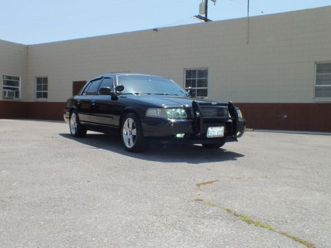 2003 Ford Crown Victoria - Front-quarter angle of lowered black sedan, push bar mounted, building behind