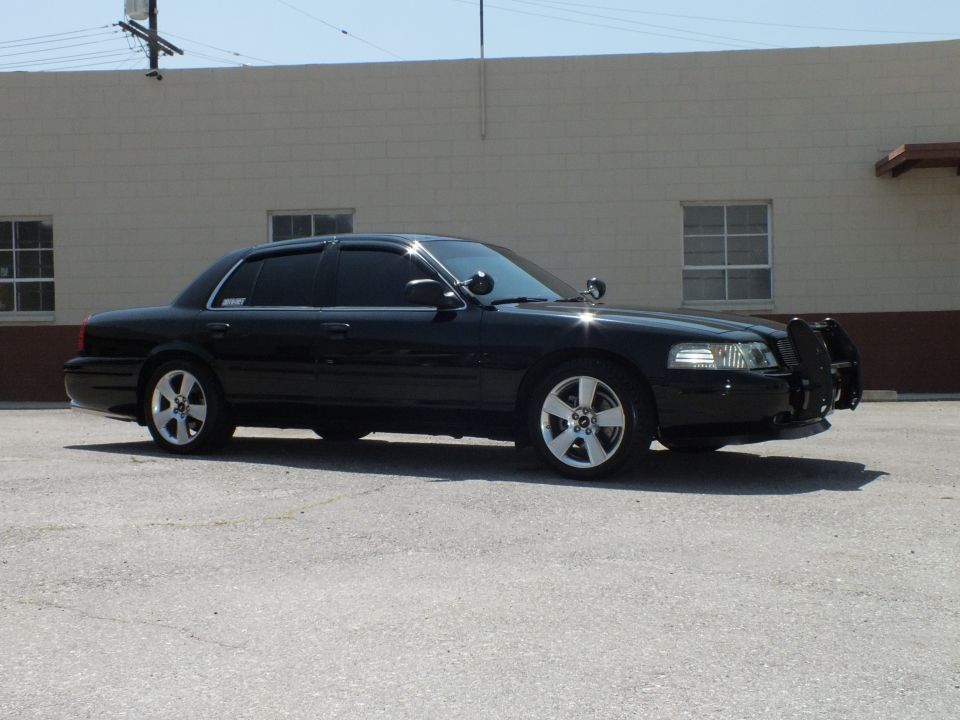Black Ford Crown Victoria full passenger-side profile, chrome wheels and tinted windows