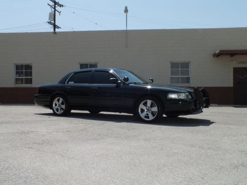 2003 Ford Crown Victoria - Full side profile of a black Crown Victoria, antennas on trunk, grille guard up front
