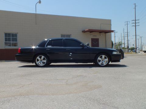 2003 Ford Crown Victoria - Left-side view of black sedan beside masonry building, power lines overhead