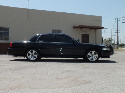 2003 Ford Crown Victoria - Left profile of glossy black Crown Victoria parked on cracked asphalt