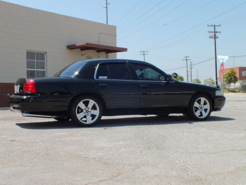 2003 Ford Crown Victoria - Rear-right view of lowered black Crown Victoria, dual taillights, power poles behind