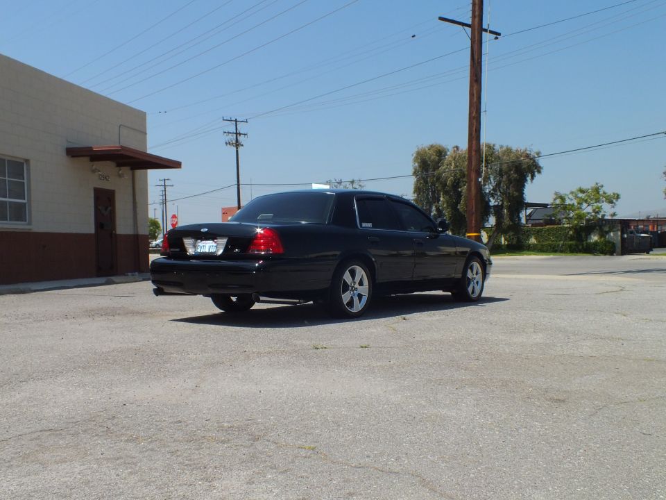 Black Ford Crown Victoria rear-quarter view, California plate and chrome wheels visible